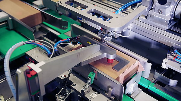 close up of a machine in a factory being used to create cardboard packaging